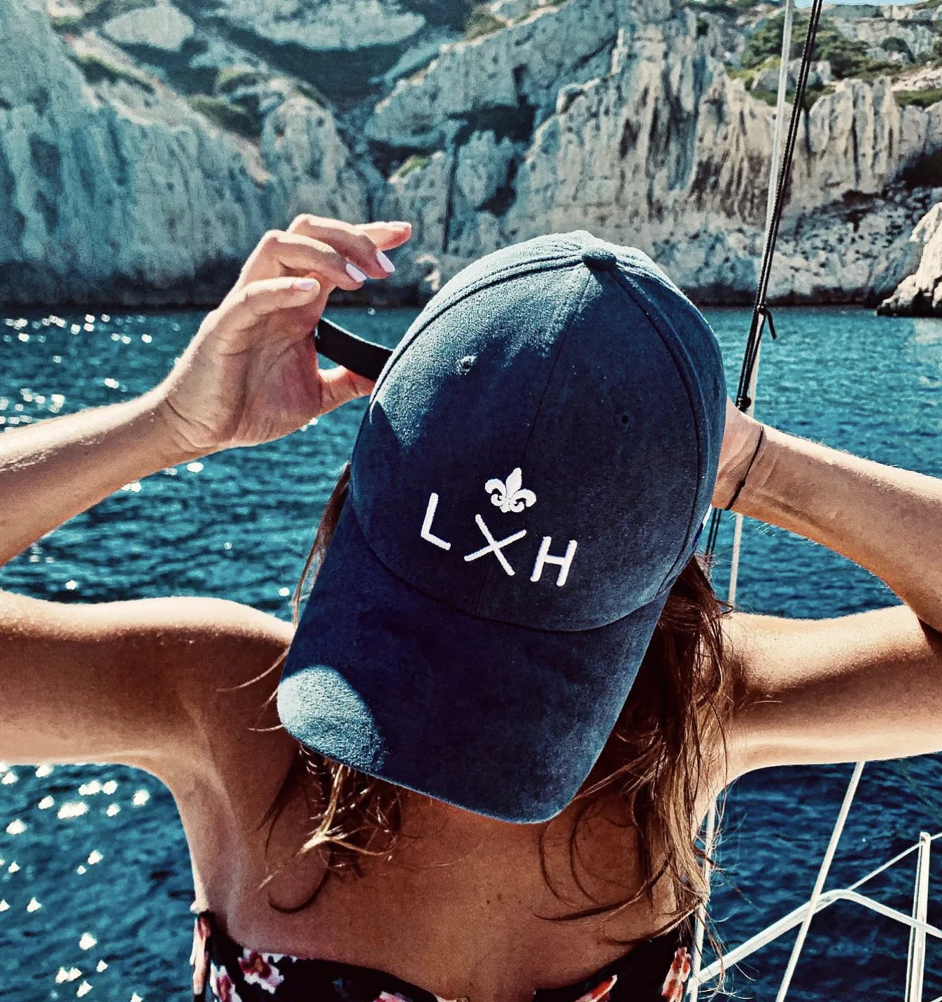 Une casquette LXH tenue à bout de bras à l'avant d'un bateau
