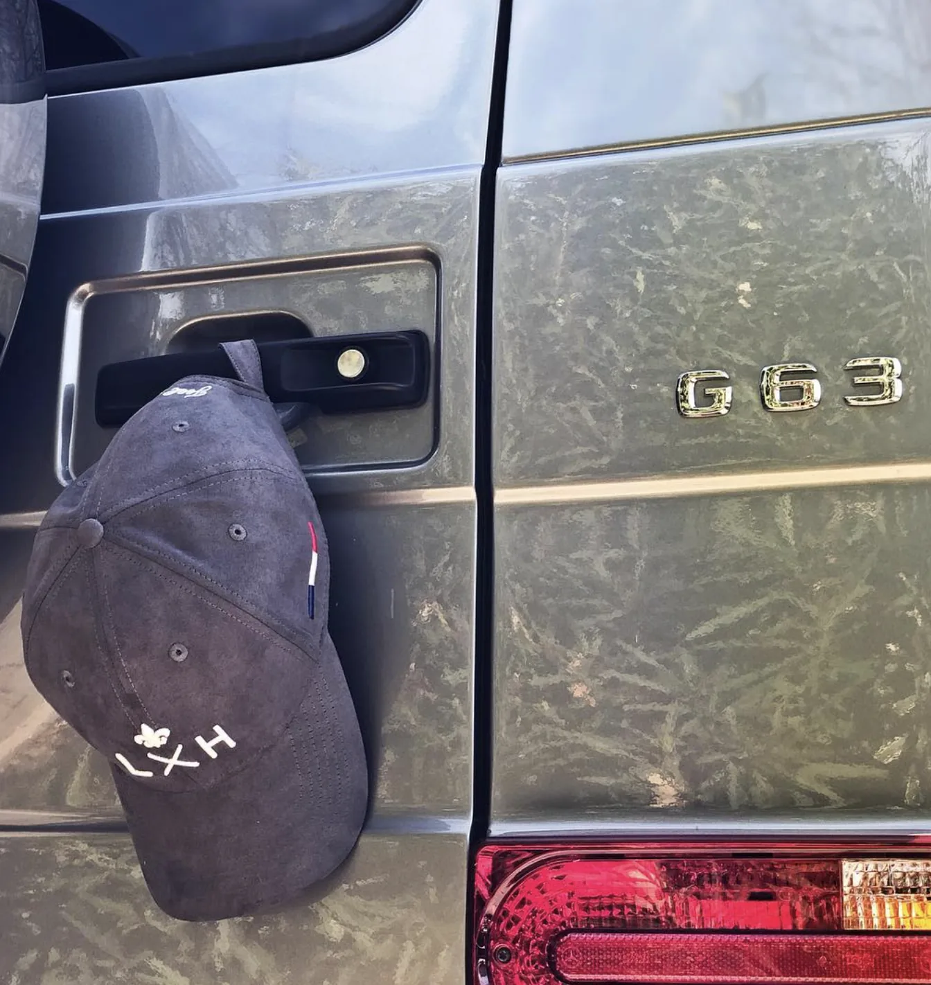 Une casquette LXH posée sur l'aile d'une Mercedes G63