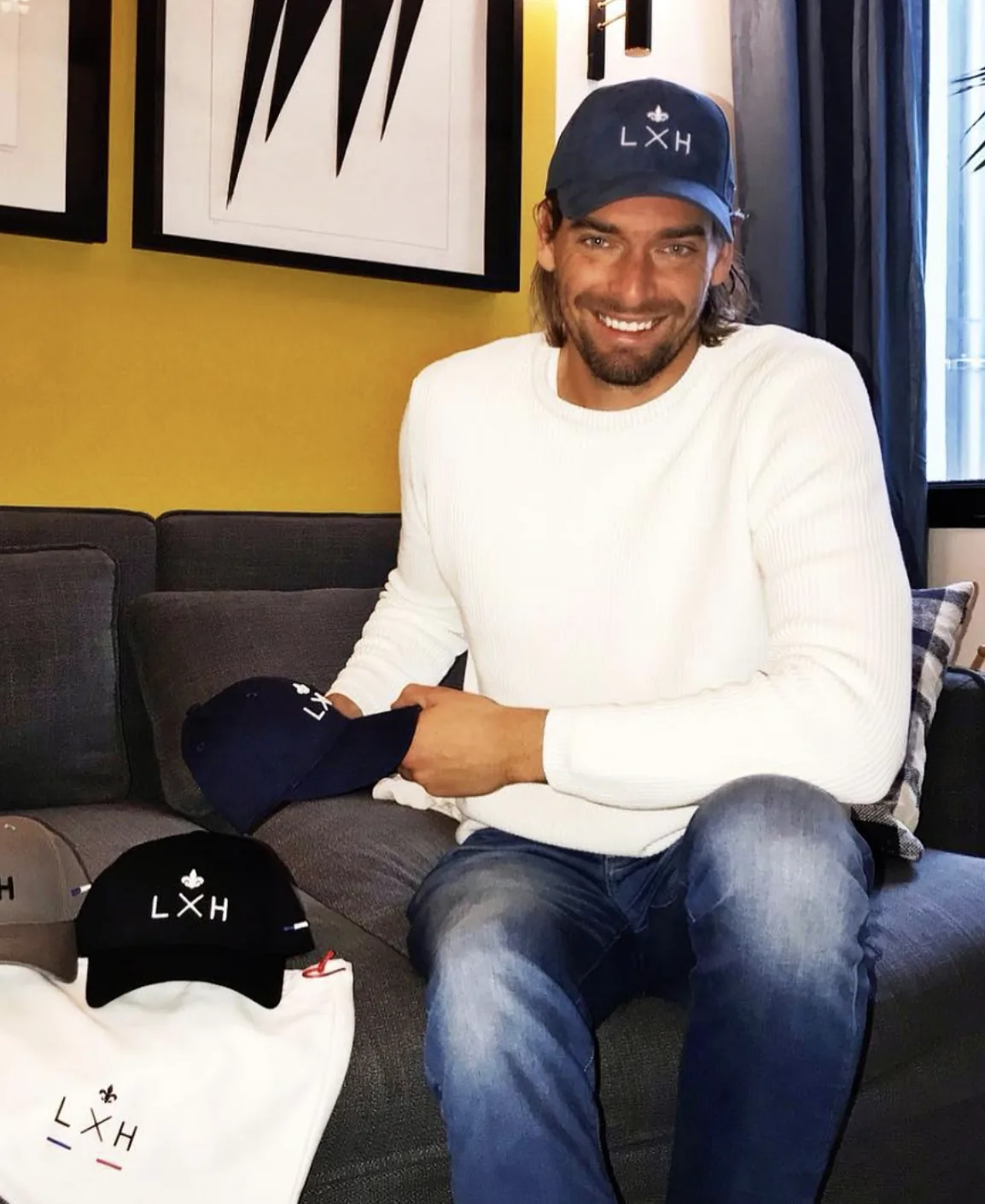 Un homme assis chez lui, ses casquettes LXH sorties de leur boîte